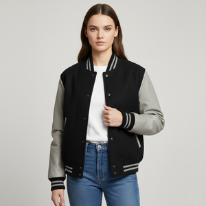 Woman wearing a black and gray varsity jacket on a light gray background
