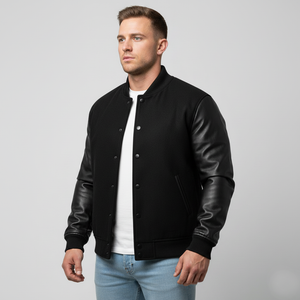 Man wearing a black varsity jacket with leather sleeves on a gray background