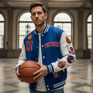 Man holding a basketball wearing a Pistons letterman jacket in an indoor setting