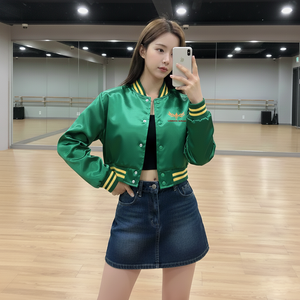 Woman taking a mirror selfie wearing a green jacket with yellow accents and a denim skirt in a dance studio.