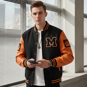 Man wearing a black and orange varsity jacket with a 'M' logo, standing indoors.