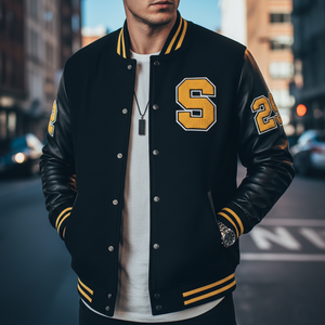 Person wearing a black varsity jacket with yellow accents in an urban setting