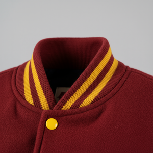 Close-up of a maroon jacket with yellow stripes on the collar against a gray background