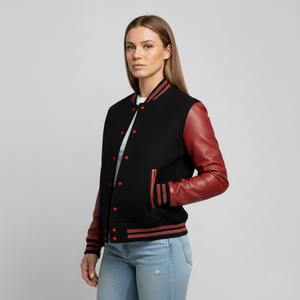 Woman wearing a black and red varsity jacket with leather sleeves on a gray background