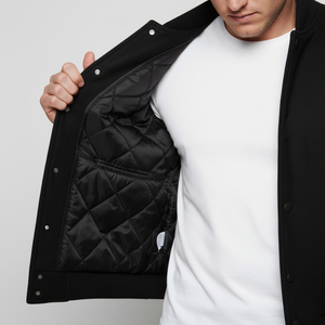 Person wearing a black quilted jacket over a white shirt on a light gray background