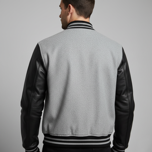 Gray varsity jacket with black leather sleeves on a gray background