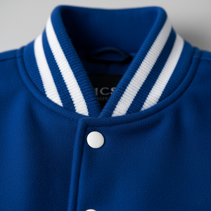 Close-up of a blue varsity jacket with white stripes on the collar against a gray background.
