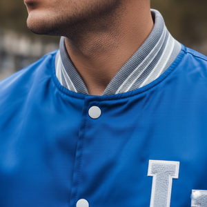 Close-up of a blue jacket with a letter 'I' on the chest, worn by a person.