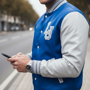 Person wearing a blue and white letterman jacket with a logo, holding a phone on a blurred street background.