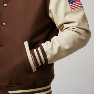 Brown and beige varsity jacket with American flag patch on sleeve against a light gray background