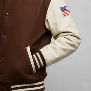 Brown and beige varsity jacket with American flag patch on sleeve against a gray background