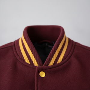 Maroon jacket with gold trim and button on a gray background