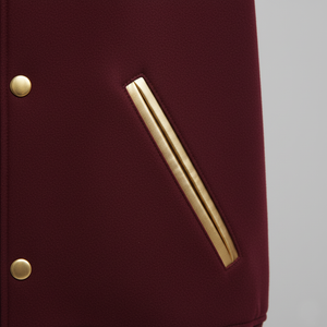 Maroon jacket with gold buttons and a gold stripe on a gray background