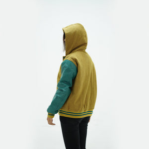 Back view of camel and green women's hooded letterman jacket displaying wool body and green leather sleeves with ribbed waistband