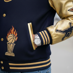 Navy and gold varsity jacket with a basketball and torch emblem, worn by a person.