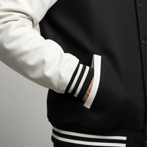 Close-up of a black varsity jacket with white stripes on a plain background