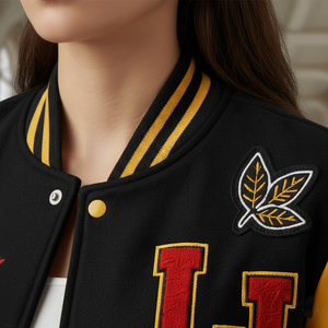 Close-up of a black varsity jacket with red letters and yellow accents on a mannequin.
