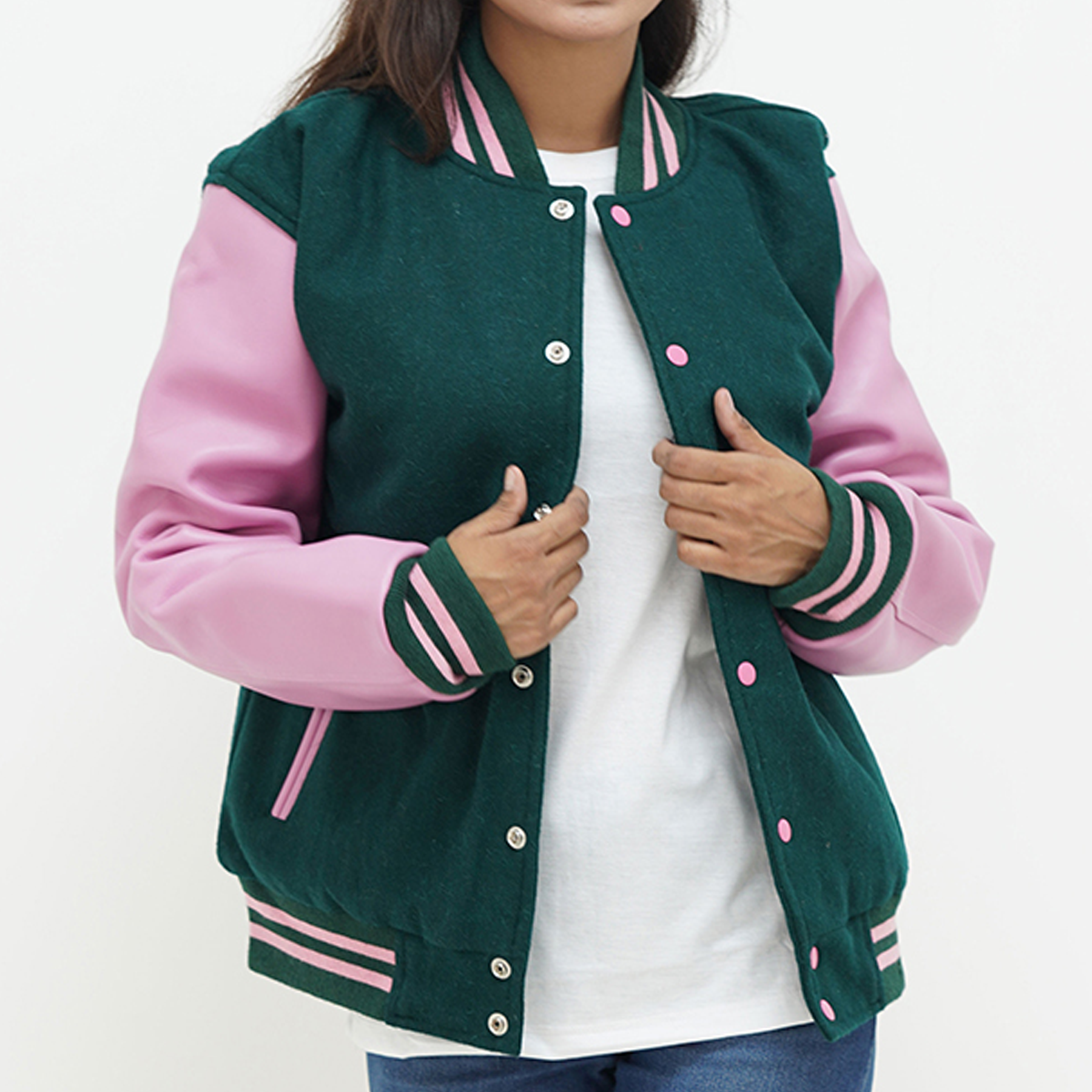 A woman wearing a dark green baseball varsity letterman jacket with pink leather sleeves and a ribbed collar. The jacket features a front with snap-button fastening and two side pockets.