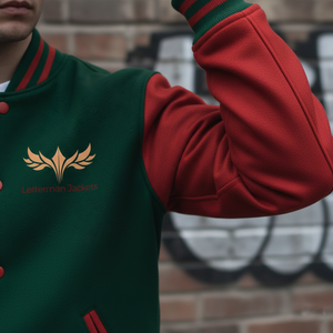 Person wearing a green and red jacket with a logo, standing against a brick wall.