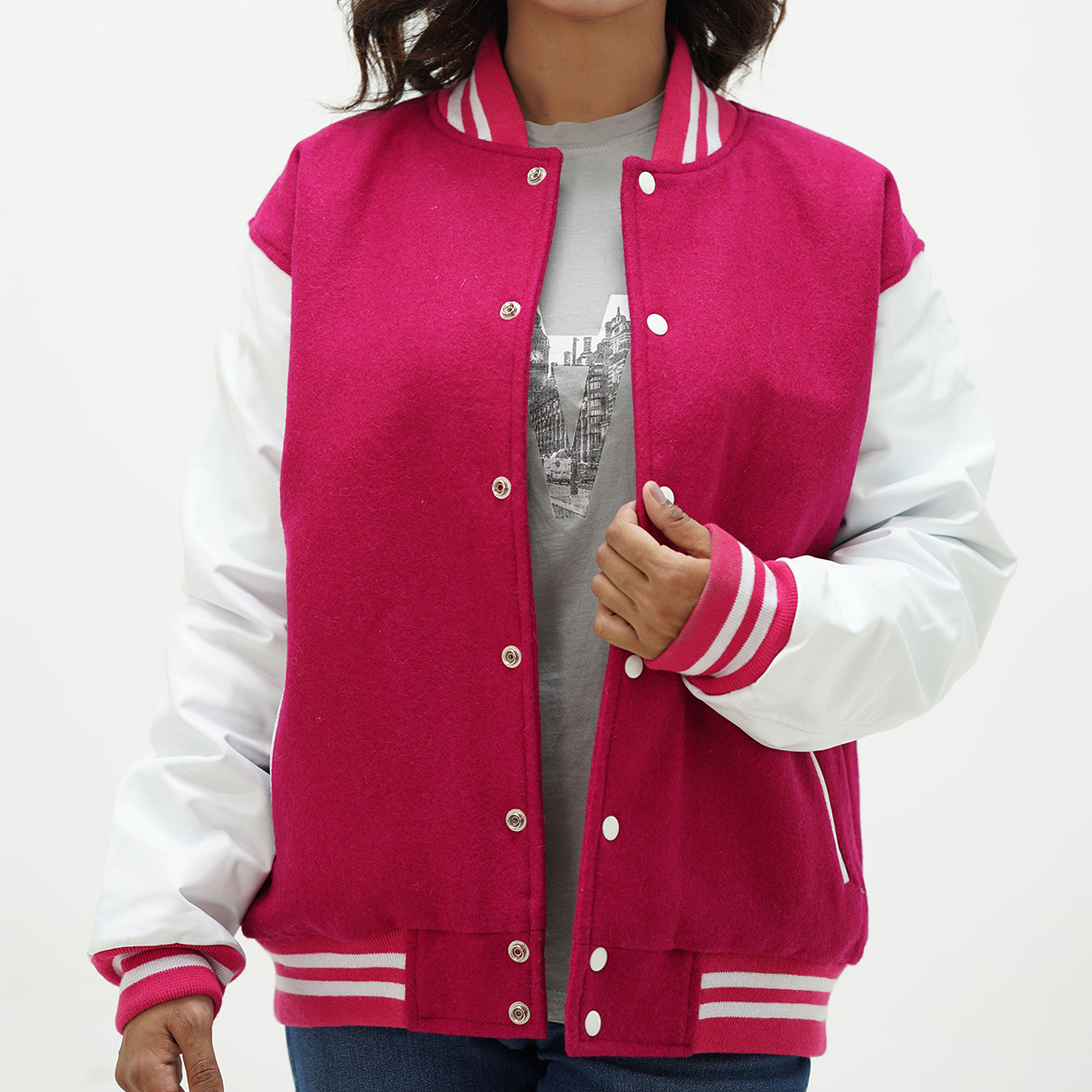 A girl wearing a pink and white collegiate letterman jacket with leather arms and a wool body. The jacket features a quilted diamond lining, a classic ribbed collar, and coated snap-button fastening.