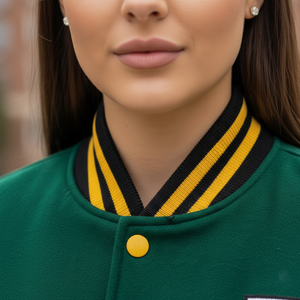 Close-up of a person wearing a green varsity jacket with a yellow and black striped collar.