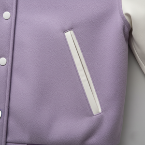 Close-up of a purple jacket with white zipper and buttons on a light gray background