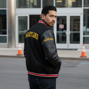 Man wearing a black 'Maryland' letterman jacket standing in front of a building with traffic cones.