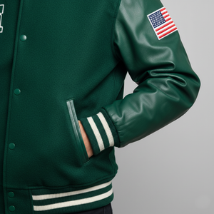 Green varsity jacket with American flag patch on sleeve against a gray background