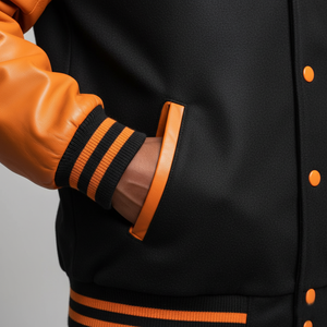 Close-up of a black and orange varsity jacket with leather sleeves.