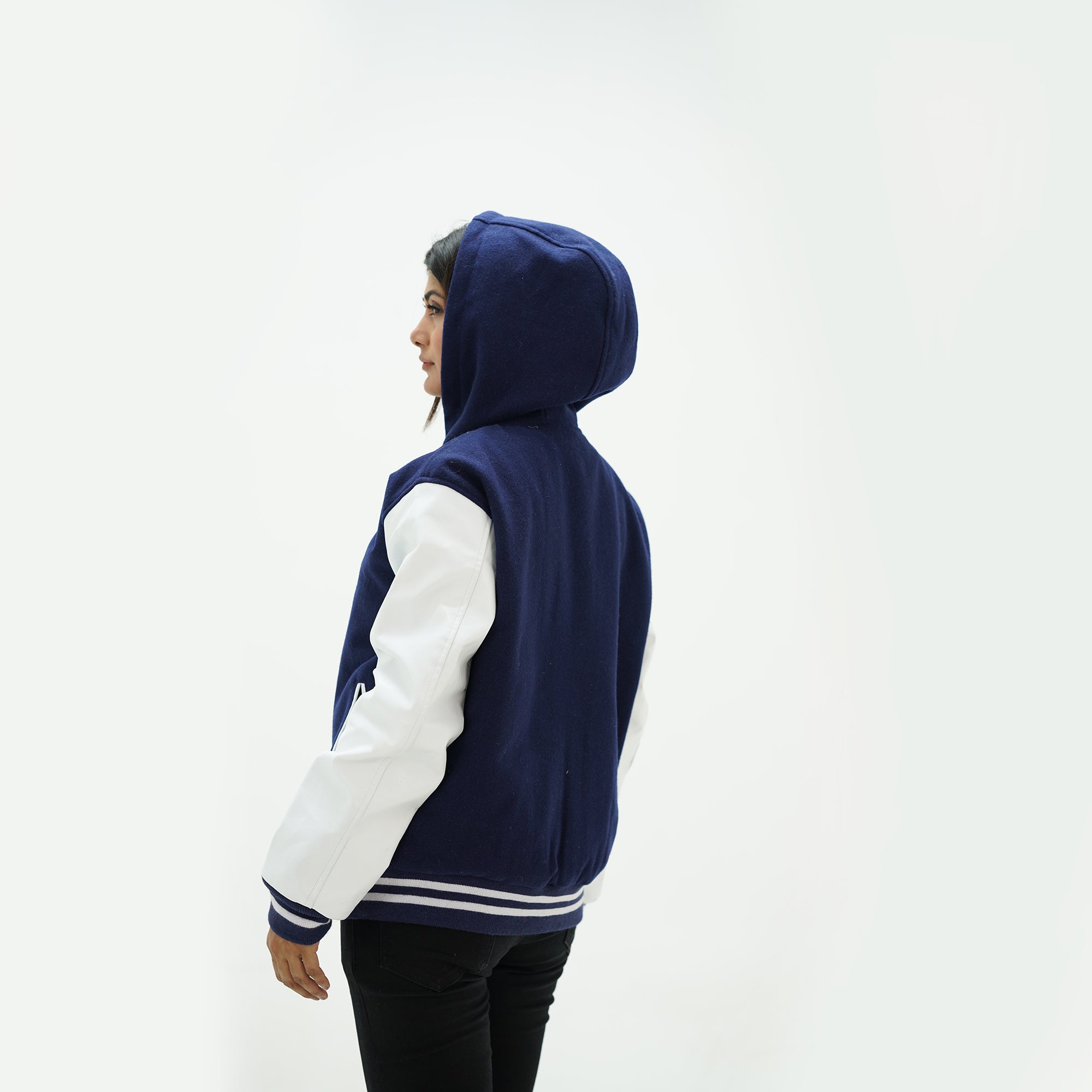 Back view of women's navy blue varsity jacket with hood displaying wool body and white leather sleeves with ribbed waistband