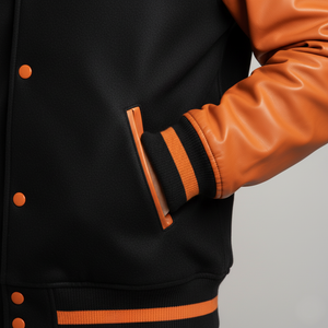 Black varsity jacket with orange accents on a gray background