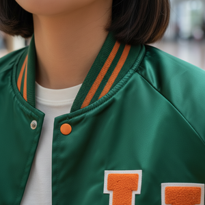 Green letterman jacket with orange accents and a large 'LJ' on a blurred background