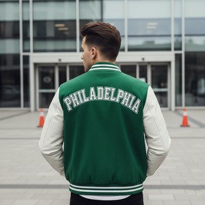 Person wearing a green and white 'Philadelphia' letterman jacket standing in front of a building.