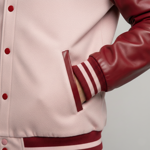 Close-up of a beige and red varsity jacket with leather sleeves on a neutral background
