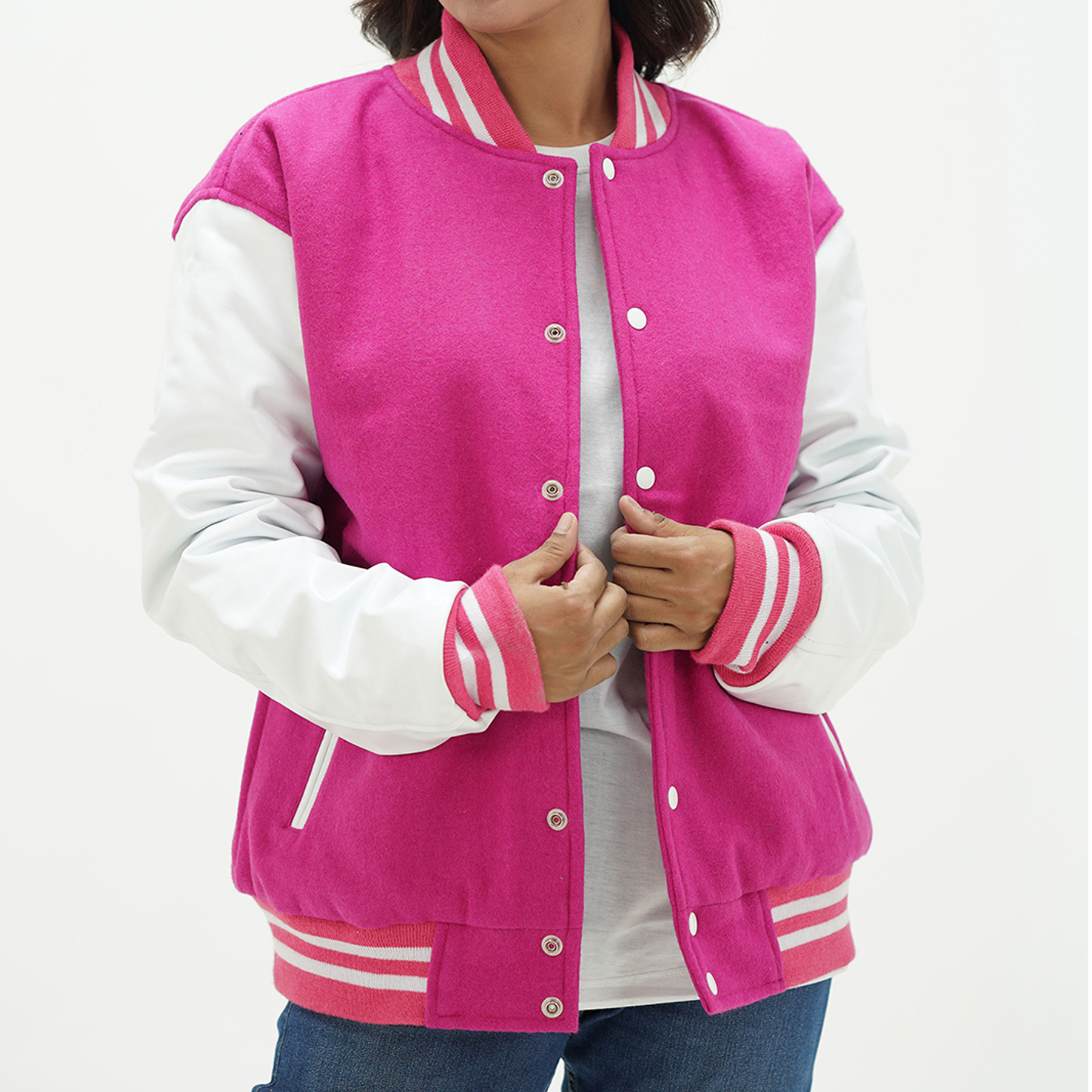 A woman wearing a pink and white letterman jacket with leather sleeves, featuring a quilted design, ribbed cuffs and hem, and two side pockets.