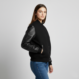Woman wearing a black bomber jacket with leather sleeves on a gray background