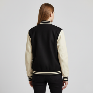 Person wearing a black and cream varsity jacket on a light gray background