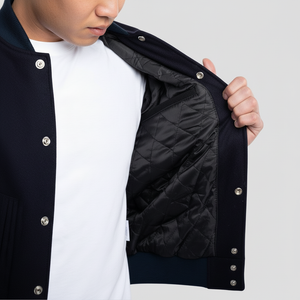 Person wearing a black quilted jacket with white buttons on a light gray background