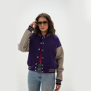 Close-up detail of purple and gray crop varsity jacket featuring wool and leather sleeve junction with ribbed collar on cropped style