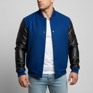 Man wearing a blue varsity jacket with black leather sleeves on a gray background