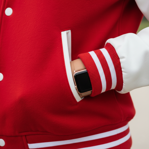 Person wearing a red varsity jacket with a white stripe, holding a smartwatch.