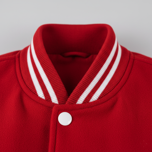Close-up of a red varsity with a white strips button and collar against a gray background