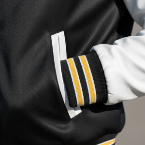 Close-up of a black jacket with white cuffs and yellow stripes, worn by a person.