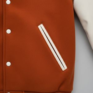 Close-up of a brown jacket with white buttons and trim on a light gray background