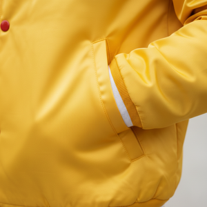 Close-up of a yellow jacket with a white interior lining on a light gray background