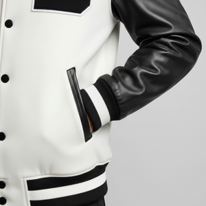 White varsity jacket with black leather sleeves on a light gray background