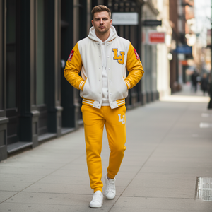 Man wearing a yellow and white varsity jacket with 'LJ' logo on a city street.
