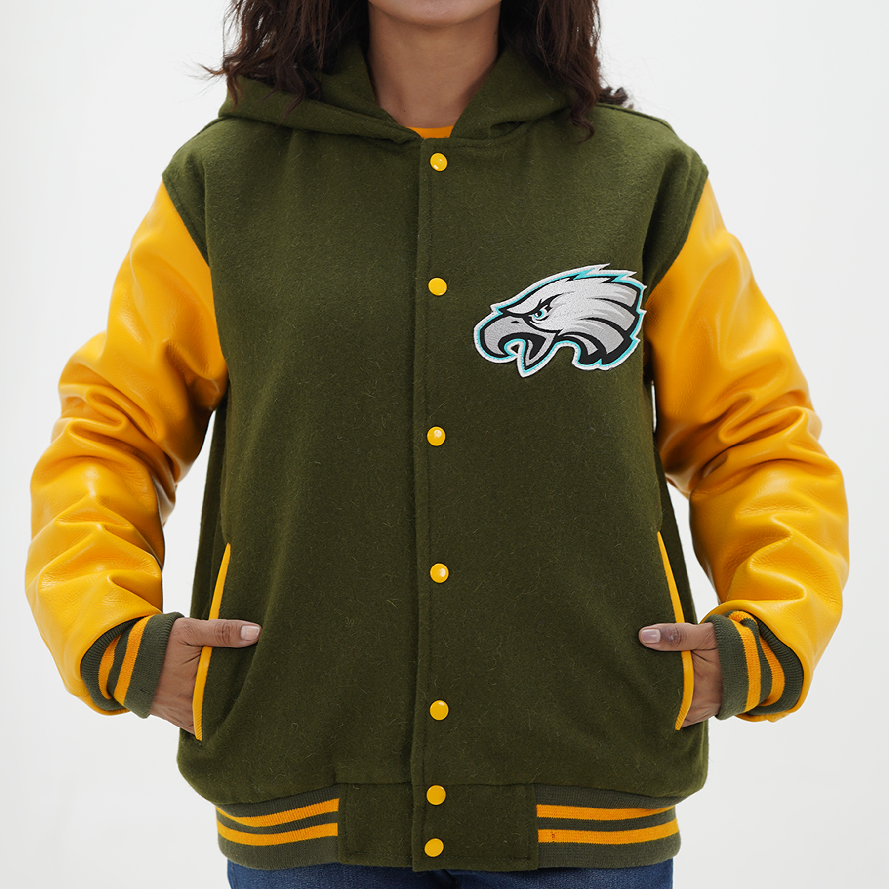 A woman wearing a green and yellow Philadelphia Eagles varsity jacket with leather arms and a wool body, featuring a front snap closure and yellow rib with stripes.
