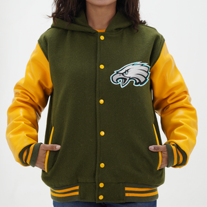 A woman wearing a green and yellow Philadelphia Eagles varsity jacket with leather arms and a wool body, featuring a front snap closure and yellow rib with stripes.