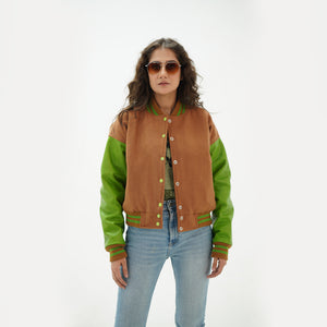 Three-quarter view of women's brown and parrot green varsity jacket highlighting snap buttons, side pockets, and unique brown-parrot green color pairing